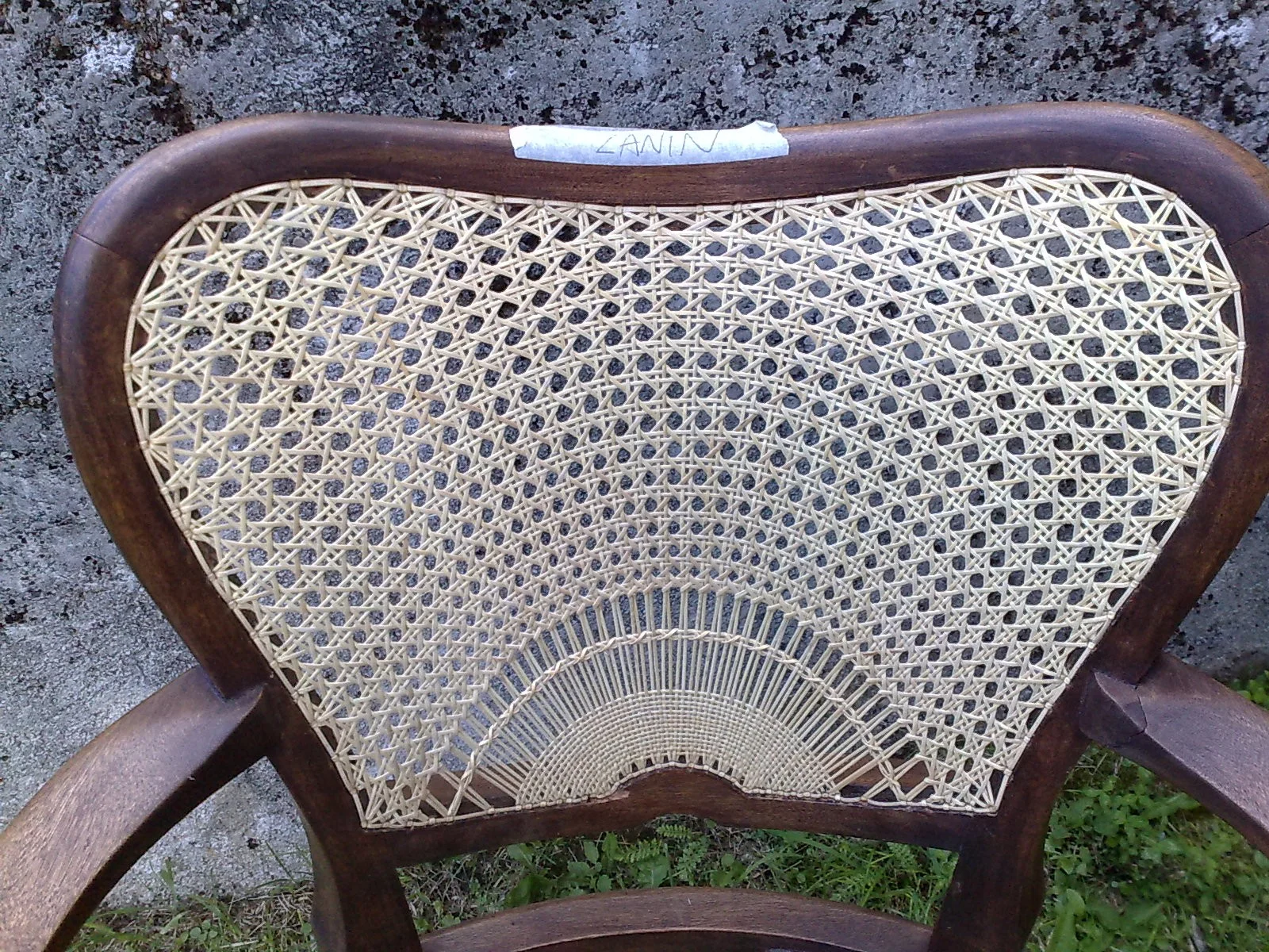 Detail of a woven chair back with strands spreading into a fan pattern