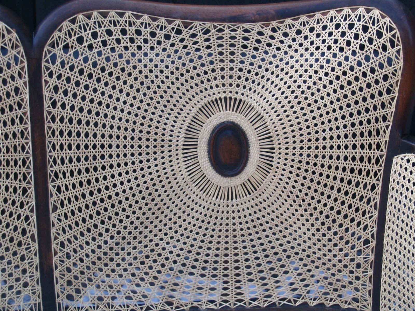 Close view of radial cane weaving around an oval medallion
