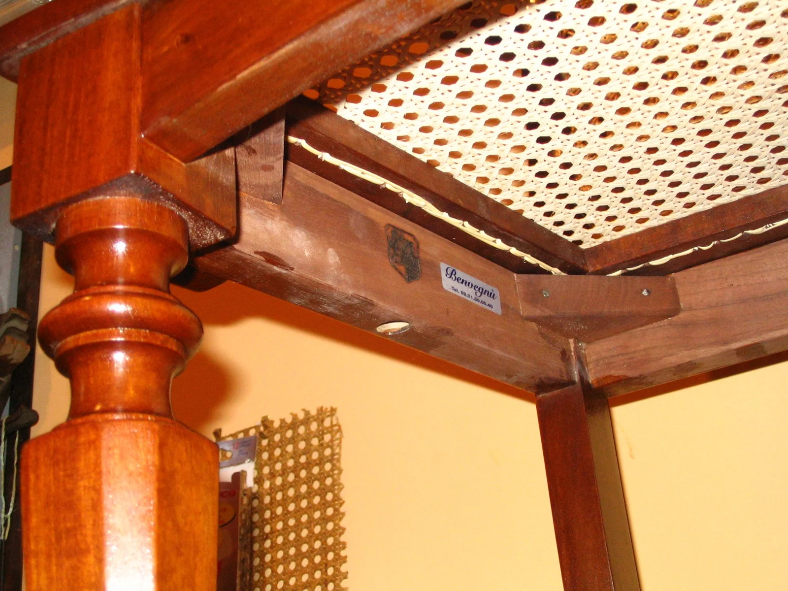 Underside of a wooden chair showing the seat frame and label