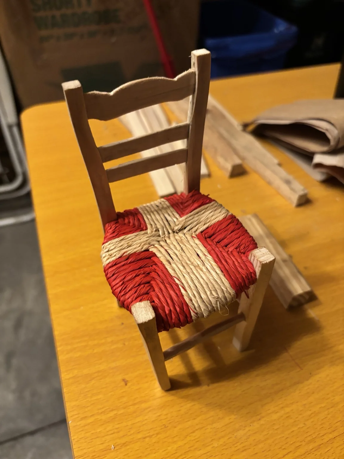 Handmade wooden miniature chair with red and natural raffia seat