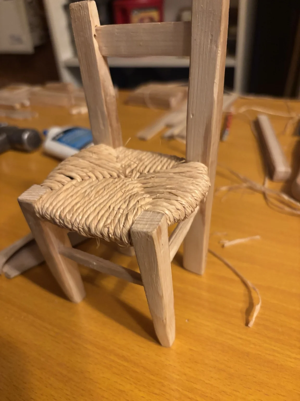 Handmade wooden miniature chair with a natural-colour woven raffia seat